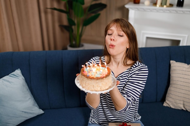 젊은 백인 여자 생일 소원을 만들고 케이크에 촛불을 불고