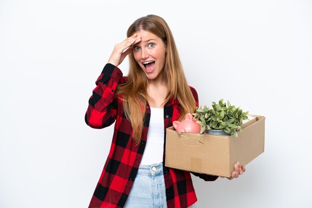 Young caucasian woman making a move while picking up a box full of things isolated on white background with surprise expression