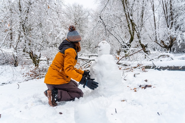 A young Caucasian woman making a snowman in the snowy forest of the Artikutza natural park in Oiartzun