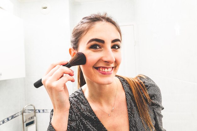 Young caucasian woman making up herself before a going night party in the bathroom