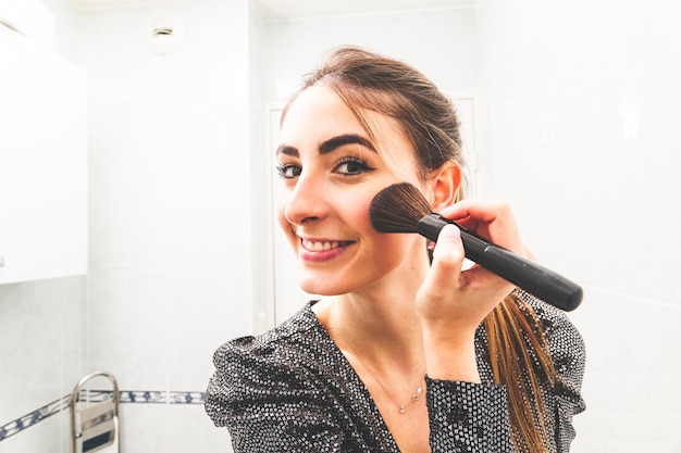 Young caucasian woman making up herself before a going night party in the bathroom