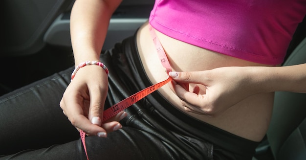 Young caucasian woman measuring her belly