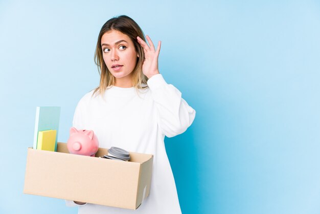 Young caucasian woman moving home isolated trying to listening a gossip.