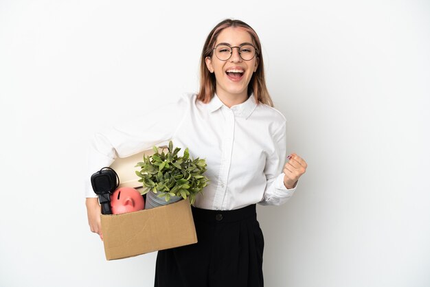 Young caucasian woman moving in new home among boxes isolated on white background celebrating a victory in winner position