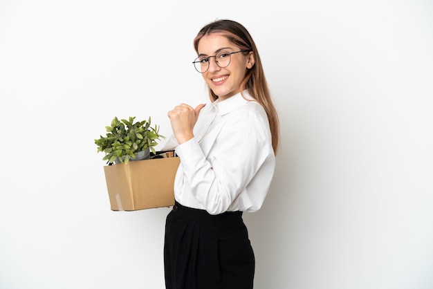 Young caucasian woman moving in new home among boxes isolated on white background proud and self-satisfied