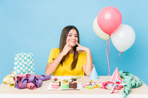 Giovane donna caucasica che organizza un compleanno dubitando tra due opzioni.