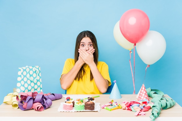 Young caucasian woman organizing a birthday shocked covering mouth with hands.