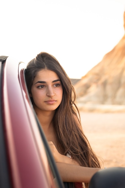 Young caucasian woman outside a car window in Bardenas Reales desert. Navarra, Basque Country.