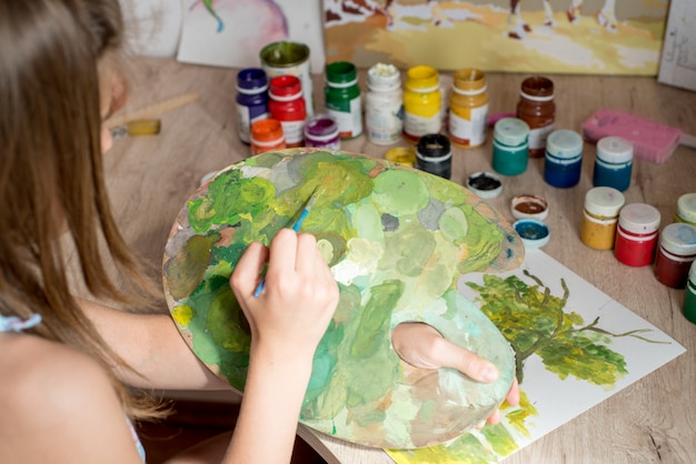 Young Caucasian woman painter working in canvas in art studio