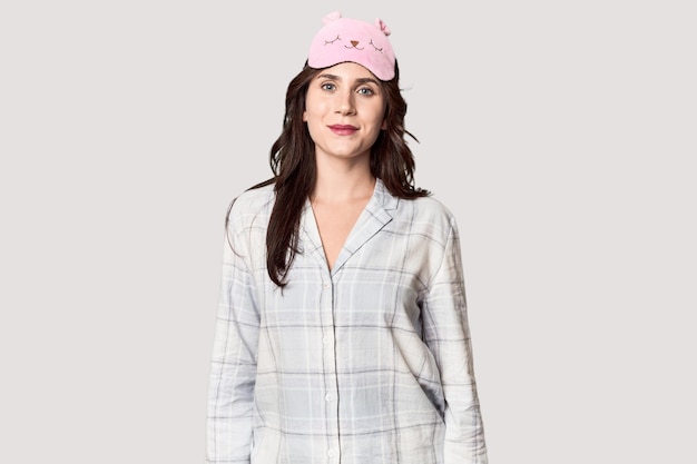 Photo young caucasian woman in pajamas with sleep mask in studio