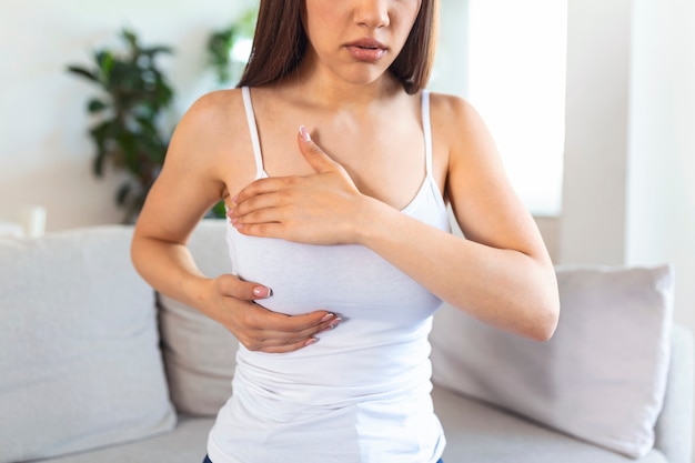 Young caucasian woman palpating her breast by herself that she concern about breast cancer. Healthcare and breast cancer concept