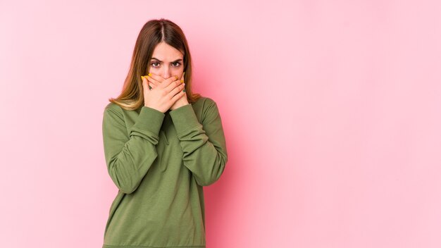 Young caucasian woman on pink covering mouth with hands looking worried.