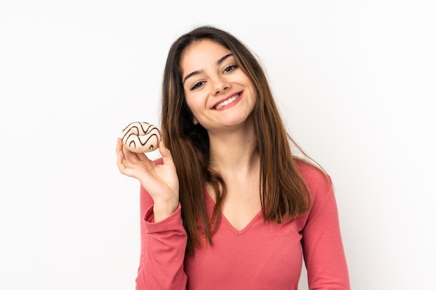 Young caucasian woman on pink wall holding a donut and happy