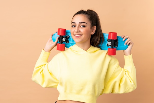 Young caucasian woman on pink wall with a skate with happy expression