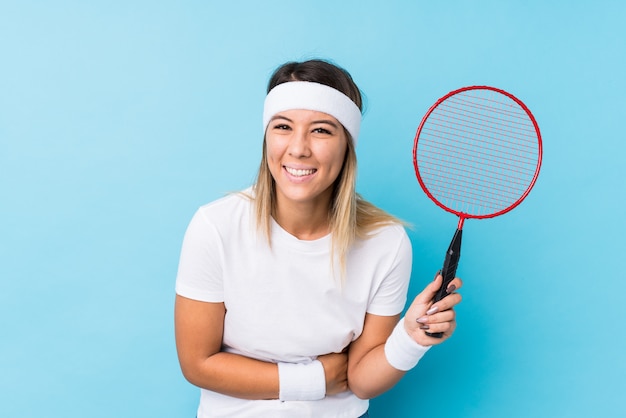 Young caucasian woman playing badminton isolated laughing and having fun.