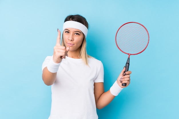 Young caucasian woman playing badminton isolated showing number one with finger.