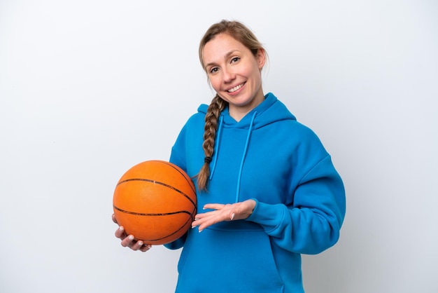 Young caucasian woman playing basketball isolated on white background extending hands to the side for inviting to come