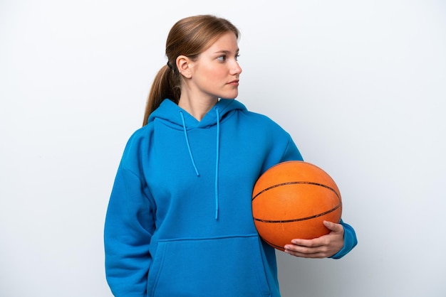 Young caucasian woman playing basketball isolated on white background looking to the side