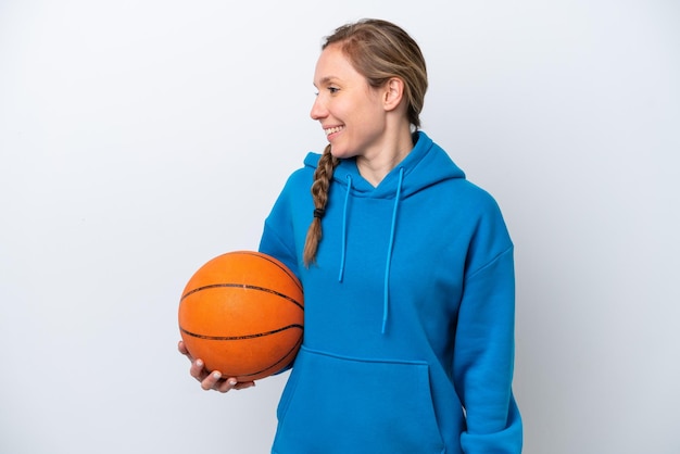 Young caucasian woman playing basketball isolated on white background looking side