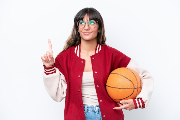 Young caucasian woman playing basketball isolated on white background pointing up a great idea