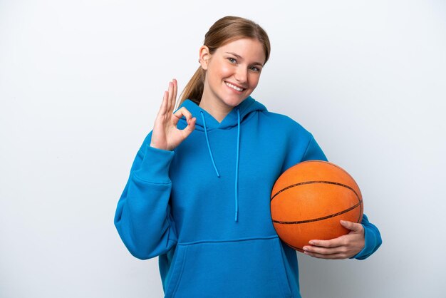 Young caucasian woman playing basketball isolated on white background showing ok sign with fingers