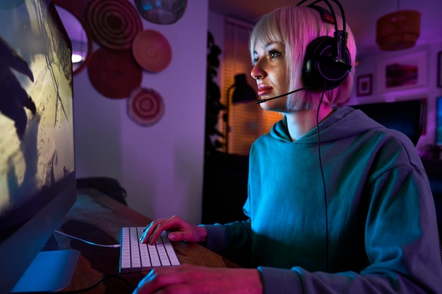 Young caucasian woman playing game at night on Desktop PC