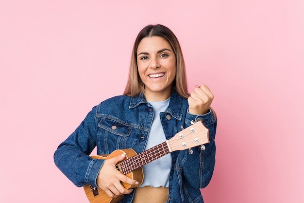 Young caucasian woman playing ukelele cheering carefree and excited.
