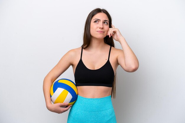 Young caucasian woman playing volleyball isolated on white background having doubts and thinking