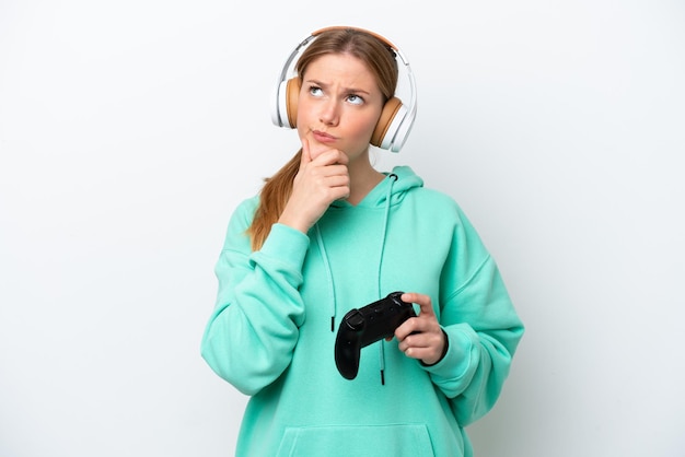 Young caucasian woman playing with a video game controller isolated on white background having doubts