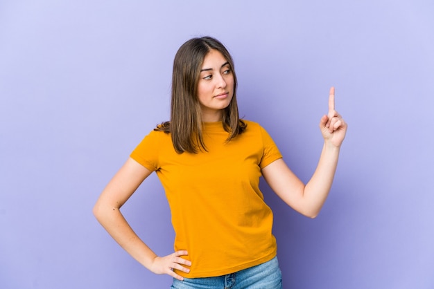 Young caucasian woman pointing with finger at you as if inviting come closer.