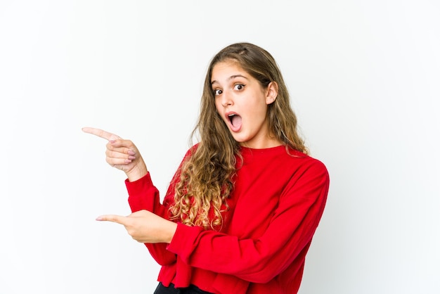 Young caucasian woman pointing with forefingers to a copy space, expressing excitement and desire.