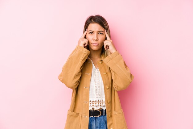 Young caucasian woman posing isolated focused on a task, keeping forefingers pointing head.