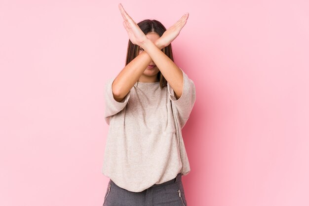 Young caucasian woman posing isolated keeping two arms crossed, denial concept.