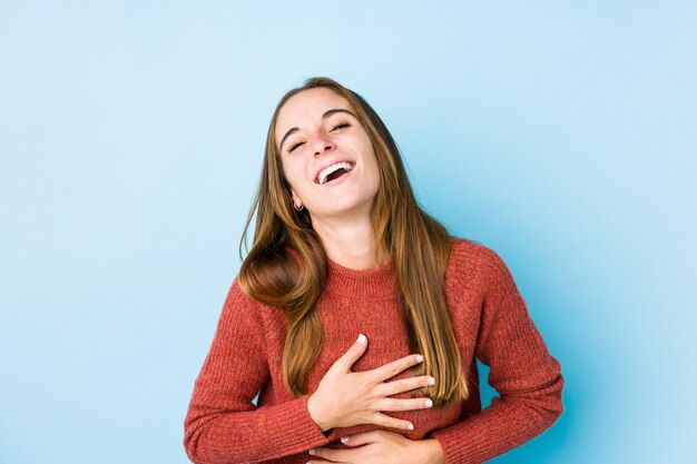 Young caucasian woman posing isolated  laughs happily and has fun keeping hands on stomach.