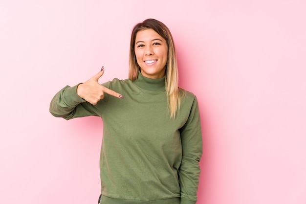 Young caucasian woman posing isolated  person pointing by hand to a shirt copy space, proud and confident