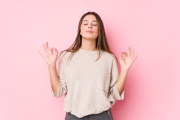 Young caucasian woman posing isolated relaxes after hard working day, she is performing yoga.