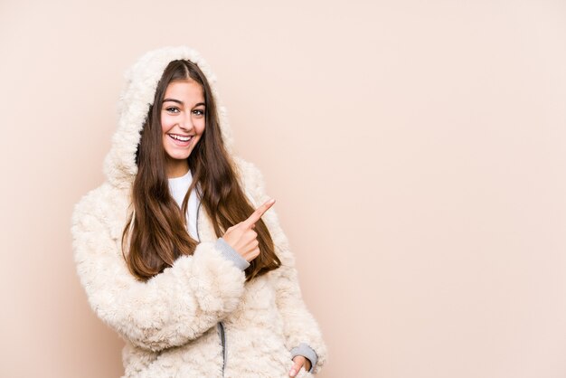 Young caucasian woman posing isolated smiling and pointing aside, showing something at blank space.