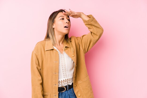 Young caucasian woman posing looking far away keeping hand on forehead.