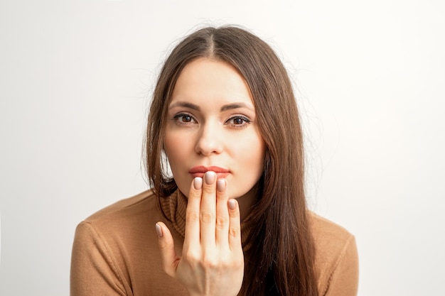 Young caucasian woman posing with fashion beige nails and sensual lips in studio.