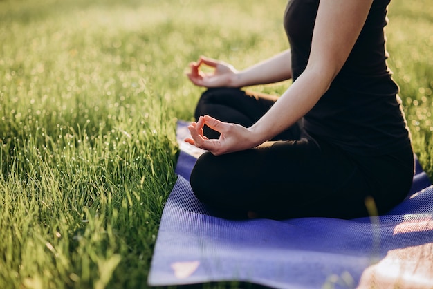 Young caucasian woman practices yoga in lotus position on an early sunny morning in a forest  Soft selective focus.