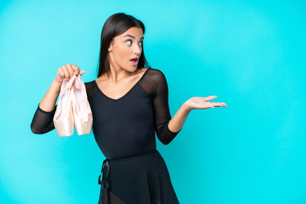 Young caucasian woman practicing ballet isolated on blue background with surprise expression while looking side