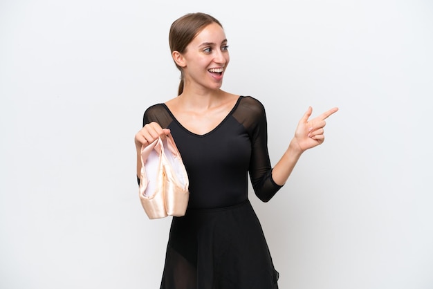 Young Caucasian woman practicing ballet isolated on white background pointing finger to the side and presenting a product