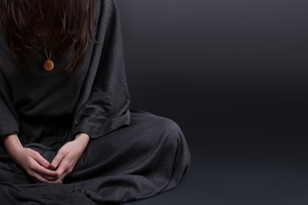 Young caucasian woman praying on black background