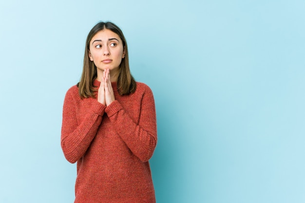 Young caucasian woman praying, showing devotion, religious person looking for divine inspiration.