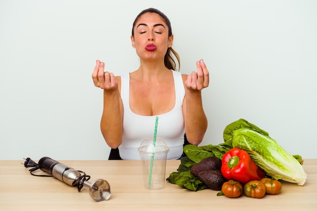 お金がないことを示す野菜を使った健康的なスムージーを準備する若い白人女性。