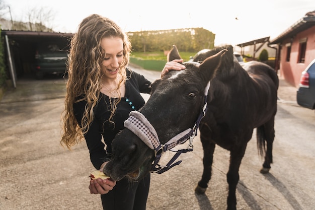 Young caucasian woman preparing a white horse for a ride