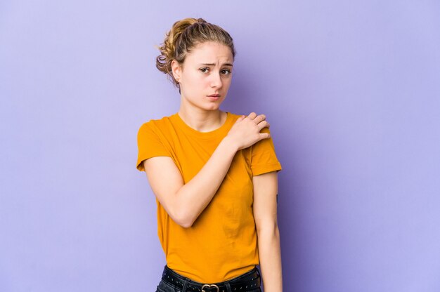 Young caucasian woman on purple having a shoulder pain.