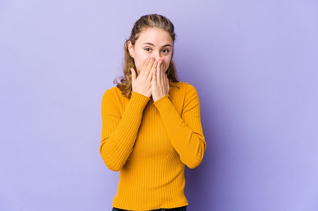 Young caucasian woman on purple laughing about something, covering mouth with hands.