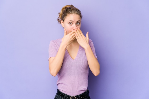 Young caucasian woman on purple shocked covering mouth with hands.