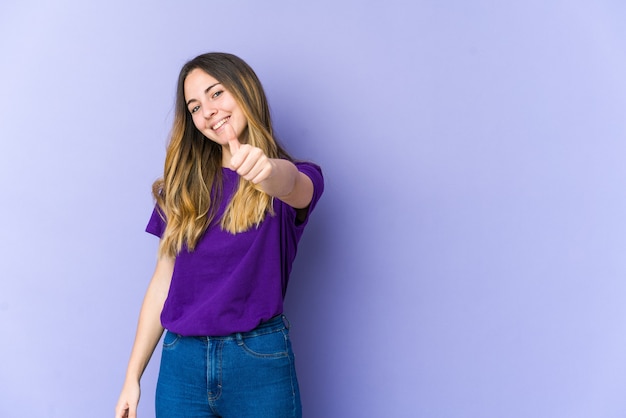 Young caucasian woman on purple smiling and raising thumb up